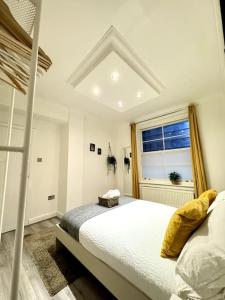 ein weißes Schlafzimmer mit einem Bett und einem Fenster in der Unterkunft Centrally-Located Gem in Marble Arch, London in London