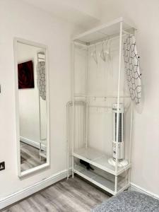 einen weißen Schrank mit einem Spiegel im Zimmer in der Unterkunft Centrally-Located Gem in Marble Arch, London in London