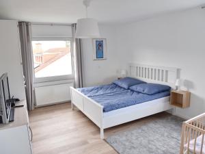 a white bedroom with a bed and a window at NEU! Ferienhaus Schaaf in Hillscheid