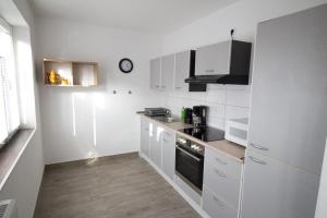 uma cozinha com electrodomésticos brancos e um relógio na parede em Liebevoll eingerichtete FeWo Alsfeld 2 em Alsfeld