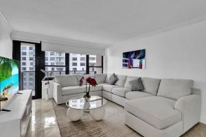 sala de estar blanca con sofá y TV en Cozy Ocean View Condo Beach Service 1015, en Miami Beach