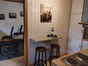 a small kitchen with stools and a counter with a bottle of wine at NEU! Sommerhaus im Cuxland in Hechthausen