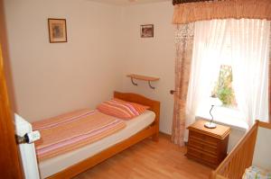 a small bedroom with a bed and a window at NEU! Ferienhaus Johann an der Nordsee in Dornum