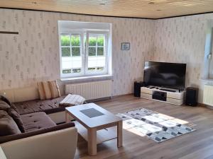 uma sala de estar com um sofá e uma televisão de ecrã plano em NEU! Ferienhaus Wattentraum mit Sauna em Dornum