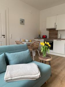 a living room with a blue couch and a table with yellow flowers at NEU Küstenliebe Friesland in Varel