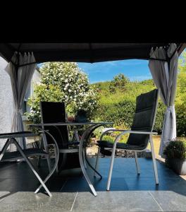 dos sillas y una mesa bajo una sombrilla en Modernes Ferienhaus Sauerblick, en Langsur