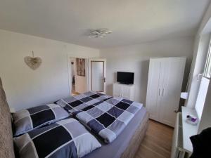 a bedroom with a black and white bed and a television at Ferienhaus Am Zollhaus in Teplingen