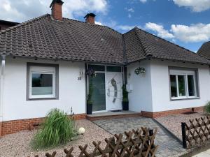 una casa blanca con una puerta y una valla en NEU Ferienwohnung MONTE in Walsrode, en Walsrode