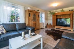 a living room with a couch and a flat screen tv at NEU! Exklusives Ferienhaus Ella in Dornum