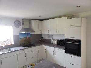 Una cocina con gabinetes blancos y un fregadero y una ventana. en Ferienhaus Kastanie mit Whirlpool Kamin und Sauna, en Blekendorf