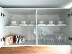 un armario blanco con platos y vasos. en NEU Ferienwohnung Walsrode en Walsrode