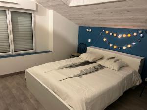 ein Schlafzimmer mit einem weißen Bett und einer blauen Wand in der Unterkunft Gîte de la Haie des Bois - 8P in Plessé