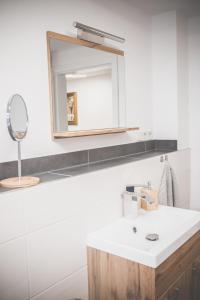 uma casa de banho com um lavatório branco e um espelho. em NEU! Moderne Ferienwohnung Knüllwald em Knüllwald