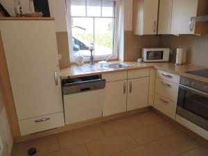 a kitchen with white cabinets and a sink and a window at NEU! Ferienhaus Küstenliebe in Harlesiel