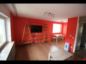 sala de estar con pared roja, TV y escalera. en NEU! Ferienwohnung im Herzen der Pfalz, en Kaiserslautern