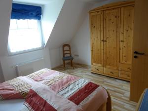 Un dormitorio con una cama y una ventana y una silla. en NEU Das Ferienhaus, en Dornumergrode
