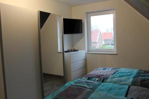 ein kleines Schlafzimmer mit einem Bett und einem Fenster in der Unterkunft NEU! Ferienhaus Sonnenschein am Badesee in Aurich