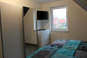 a small bedroom with a bed and a window at NEU! Ferienhaus Sonnenschein am Badesee in Aurich