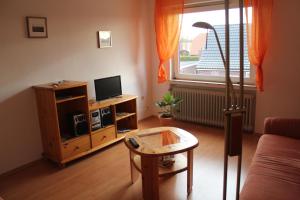 a living room with a couch and a tv and a table at NEU! Ferienwohnung im Leegmoor in Aurich