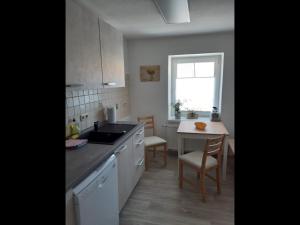 een keuken met witte kasten en een tafel en een raam bij NEU! Ferienwohnung Hanka in Crostwitz