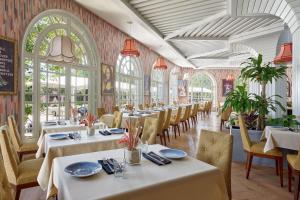 un ristorante con tavoli e sedie bianchi e finestre di Fes Marriott Hotel Jnan Palace a Fes