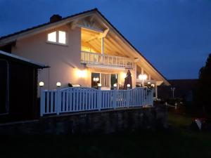ein Haus mit einem weißen Geländer und einer Veranda in der Nacht in der Unterkunft NEU Ferienwohnung Odenwald in Rimhorn