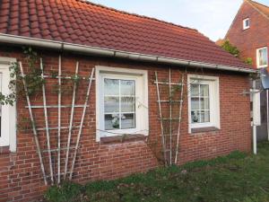 une maison en briques rouges avec trois fenêtres et un toit rouge dans l'établissement NEU Ferienhaus Torfmuttje nähe Norddeich mit Hund, à Upgant-Schott