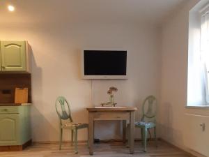 リュベナウにあるZur alten Gurkeneinlegereiのテーブルと椅子2脚、壁掛けテレビが備わる客室です。