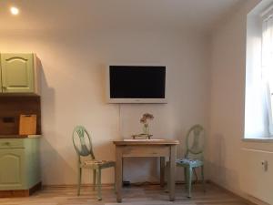a room with a table and two chairs and a tv on the wall at Zur alten Gurkeneinlegerei in Lübbenau