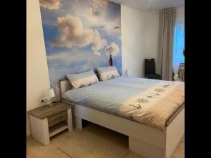 1 dormitorio con 1 cama y una pintura de nubes en NEU! Ferienhaus am Moor, en Wiesmoor