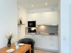 a kitchen with white cabinets and a wooden table at NEU! Appartement Wellenrauschen in Petersdorf auf Fehmarn