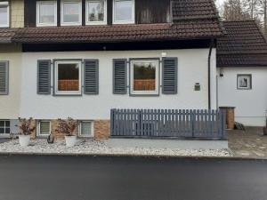 uma casa branca com uma cerca à frente. em NEU! Ferienwohnung Teichblick in Bad Grund em Bad Grund