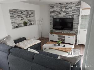uma sala de estar com um sofá azul e uma televisão em NEU! Ferienhaus Römer em Bad Sülze