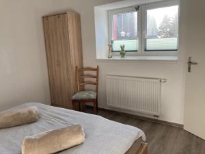 a bedroom with a bed and a chair and a window at NEU! FeWo Nähe Wismar in Lübow