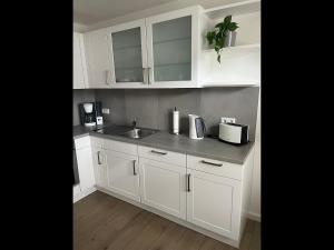 a kitchen with white cabinets and a sink at NEU! Moderne Ferienwohnung Almdorf in Almdorf