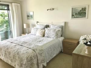 um quarto com uma cama branca com almofadas e uma janela em Sunset Point Kerikeri em Kerikeri