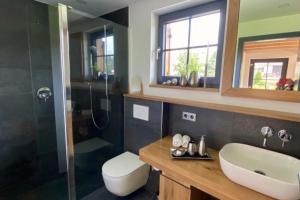 een badkamer met een wastafel, een toilet en een douche bij Die Schorenmoos-Lodge in Dietmannsried