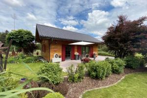 a small wooden house with a garden at Die Schorenmoos-Lodge in Dietmannsried