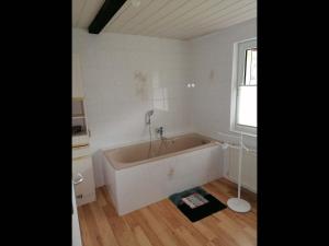 een witte badkamer met een bad en een vloer bij NEU! Morderne Ferienwohnung Hohenzieritz in Hohenzieritz