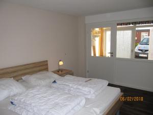 a bedroom with a bed with white sheets and a window at Ferienhaus Fahrrinne 12 in Dornum