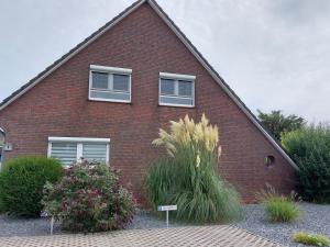a red brick house with two windows and some bushes at NEU! Fewo Merle mit Balkon in Carolinensiel