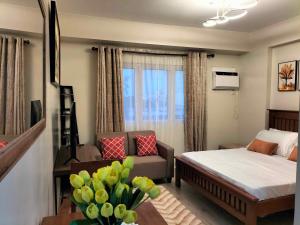 a bedroom with a bed and a living room at Ehime Suites One Regis Bacolod in Bacolod