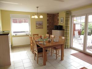 a kitchen and dining room with a wooden table and chairs at NEU Nordseeferienhaus An der Mühle in Westerholt