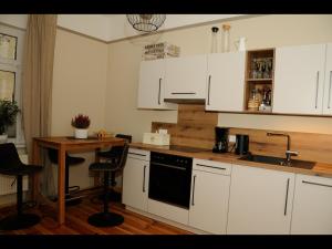 una cocina con armarios blancos y una mesa con taburetes en NEU! Stilvolle FeWo Finsterwalde, en Finsterwalde
