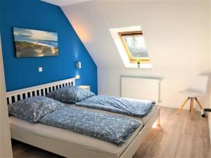 a bedroom with two beds and a blue wall at NEU! Moderne FeWo Ostseebrise Fehmarn in Petersdorf auf Fehmarn