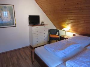 1 dormitorio con 1 cama y vestidor con TV en Ferienhaus Meerzeit, en Nessmersiel