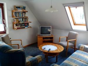 uma sala de estar com uma televisão e uma mesa e cadeiras em NEU! Nordsee-Ferienhaus Lukas em Dornum