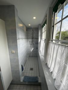 ザンデにあるNEU! Ferienwohnung Nordlichtの白いタイル張りのバスルーム(シャワー、窓付)