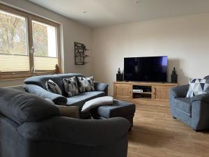 a living room with two couches and a flat screen tv at NEU! Haus am Heldrastein in Treffurt