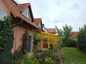 a house with a yellow porch with plants at NEU Ferienhaus mit Poolhalle und Sauna in Pyrbaum